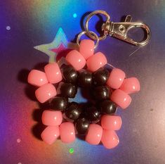 a pink and black beaded keychain is on a table with a star