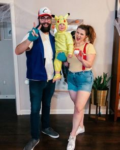 a man and woman in pokemon costumes posing for a photo with a baby on their lap