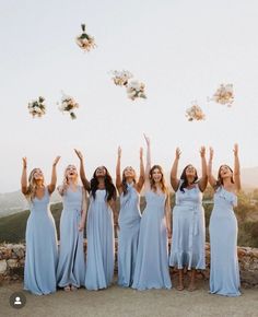 a group of women standing next to each other with their arms in the air and throwing flowers into the air