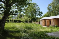 an outhouse is surrounded by tall grass and trees