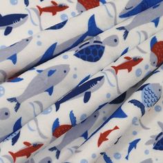 the fabric has fish on it and is white with blue, red and gray colors