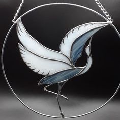 a stained glass bird hanging from a circular metal frame on a black background in the shape of a circle