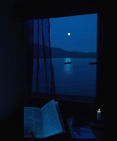 an open book sitting on top of a window sill next to a boat in the water