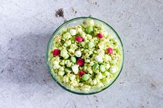 a glass bowl filled with green and red popcorn kernels on top of a table