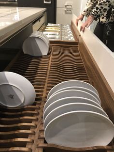 a woman standing in front of a counter filled with white dishes