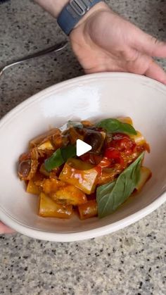 a person holding a white bowl filled with food on top of a marble countertop