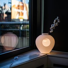 a white vase sitting on top of a window sill