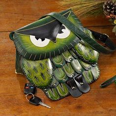 a green owl purse sitting on top of a wooden table