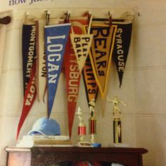 there are many pennants hanging on the wall next to a shelf with baseball memorabilia