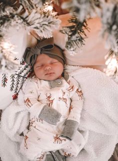 a newborn baby is sleeping under the christmas tree