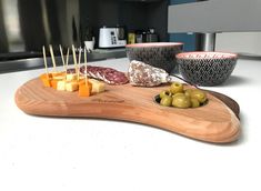 olives, cheese and meat on a cutting board with toothpicks in the foreground