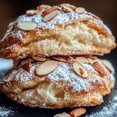 two powdered donuts stacked on top of each other with almonds and powdered sugar