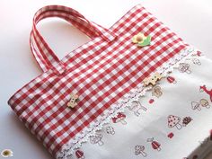 a red and white checkered bag sitting on top of a table next to a button