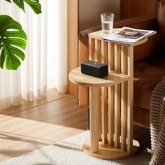 a small wooden table with a magazine on it next to a couch and potted plant