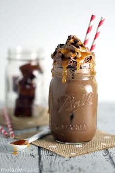 a chocolate milkshake in a mason jar with two straws on the side