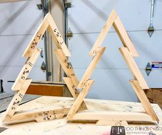 two wooden christmas trees sitting on top of a workbench with measuring tape around them