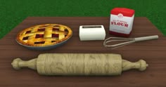 a wooden table topped with an apple pie next to a rolling pin and other items