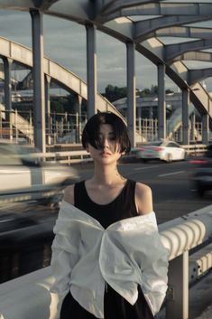 a woman standing on a bridge with her hands in her pockets