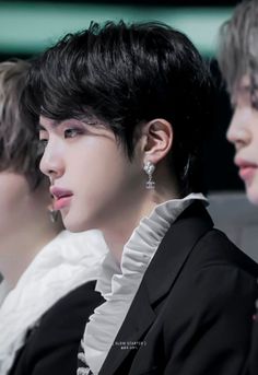 two men sitting next to each other wearing earrings