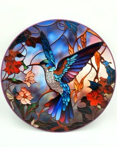 a decorative glass plate with a hummingbird on it's side and flowers in the background