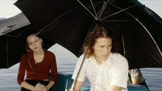 a man and woman sitting under an umbrella