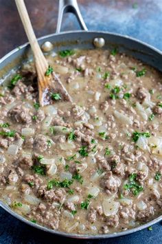 a skillet filled with meat and gravy on top of a blue table