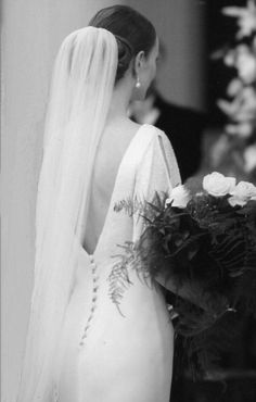 the back of a woman's wedding dress, with flowers in her hair and veil