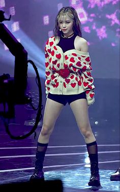 a woman standing on top of a stage wearing short shorts and a red heart sweater