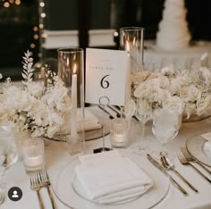 the table is set with white flowers and candles for an elegant wedding breakfast or reception