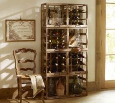 a wooden wine rack filled with bottles in a room next to a chair and window