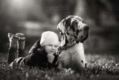 a young boy laying on the grass next to a dog