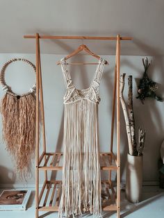 a dress hanging on a clothes rack next to a potted plant and other items