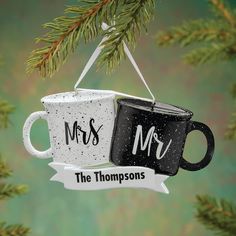 two black and white coffee mugs hanging from a christmas tree with the words mr and mrs on them