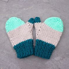 two knitted mittens sitting on top of a cement floor next to each other