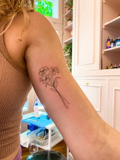 a woman's arm with a flower tattoo on the back of her left arm