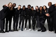 a group of people standing next to each other in front of a white background with their hands up