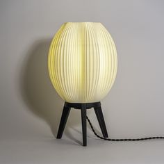 a white lamp sitting on top of a wooden table next to a black cord attached to it