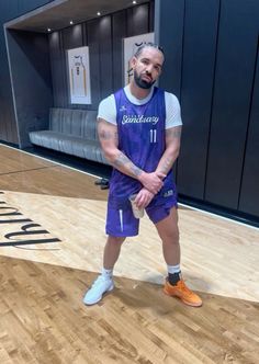 a man standing on top of a basketball court wearing a purple jersey and orange shoes