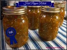 four jars filled with pickles sitting on top of a blue and white table cloth