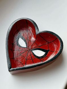 a heart shaped bowl with spiderman's face painted on it