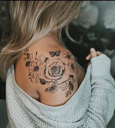 a woman with a flower tattoo on her back shoulder and neck is looking at the camera