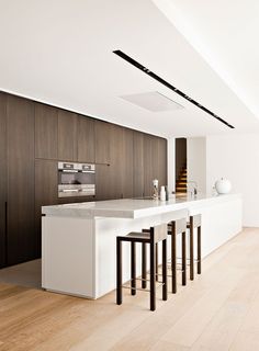 a modern kitchen with white counter tops and bar stools