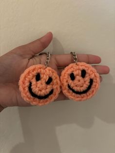 two crocheted smiley face keychains in the palm of someone's hand