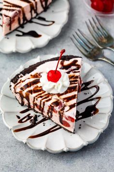 a slice of cheesecake with chocolate sauce and whipped cream on top, topped with a cherry