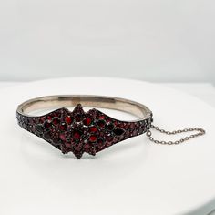 A very fine Antique Bohemian gold-filled bangle bracelet.   Prong set with garnets in a flower pattern to the top and around the circumference of the bracelet.   The bracelet opens at the middle on a hinge and is secured by both a box clasp and safety chain.  Simply a wonderful piece!  Date: 19th Century  Overall Condition: It is in overall good, as-pictured, used estate condition. There are two small garnets missing from top of flower pattern, some very fine & light surface scratches and other Garnet Bangle Jewelry Gift, Garnet Bangle Jewelry As Gift, Garnet Gemstone Bracelet Jewelry, Victorian Hinged Cuff Bangle Bracelet, Victorian Hinged Cuff Bracelet, Victorian Bangle For Ceremonial Occasions, Victorian Style Bangle As A Gift, Victorian Ceremonial Bangle Jewelry, Victorian Hinged Bangle Bracelets