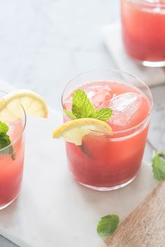 two glasses filled with watermelon lemonade and mint garnish on a white tray