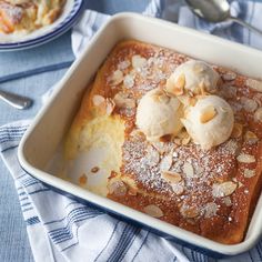 a dessert dish with almonds and powdered sugar on top, in a white casserole dish