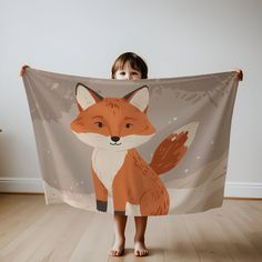 a little boy is holding up a towel with an image of a fox on it