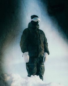 a man standing in the snow with his skis on and goggles on,