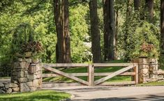 a wooden gate with two planters on top of it in front of some trees